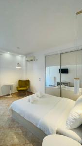 ein Schlafzimmer mit einem großen weißen Bett und einem gelben Stuhl in der Unterkunft Cozy Studio by the sea in Paleo Faliro in Athen