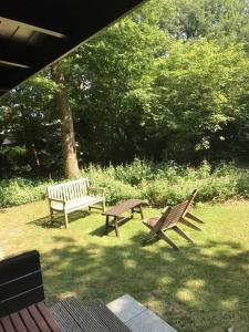 zwei Bänke im Gras in einem Park in der Unterkunft Fins Boshuis in Meppen