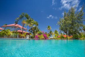 une piscine en face d'une maison avec des palmiers dans l'établissement Les Villas du Lagon, au François