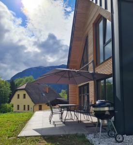a patio with a grill and a table with chairs and an umbrella at The Valley Queens in Bovec