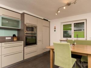 a kitchen with a wooden table and a green chair at MyHome Apartments Ambach in Oetz