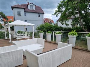 a deck with white furniture and a gazebo at Playa Baltis Międzyzdroje Apartament Katharina in Międzyzdroje