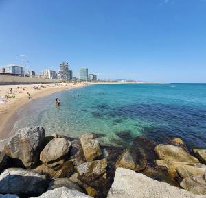 a beach with people in the water and rocks at apartment luxe MMR in Barcelona