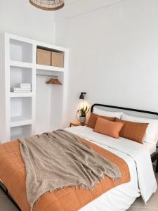 een witte slaapkamer met een groot bed met oranje kussens bij House of Hats II in Karavomylos