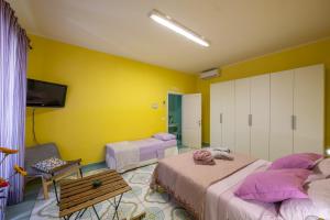 a bedroom with two beds and a yellow wall at Villa Lery Guesthouse in Agropoli