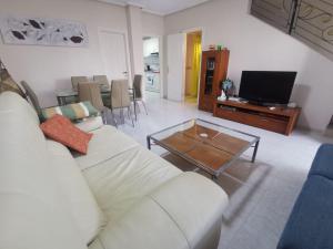 uma sala de estar com um sofá branco e uma mesa em Casa Malibu em Ciudad Quesada