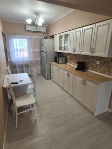 kuchnia z białymi szafkami oraz stołem i krzesłami w obiekcie Apartament ultracentral Gabriel w mieście Drobeta-Turnu Severin