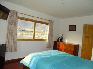 a bedroom with a blue bed and a window at Casa de Campo La Luna - Cieneguilla in Cieneguilla