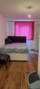 a bedroom with a bed and a pink curtain at 3 bed bedroom house with garden in Thamesmead