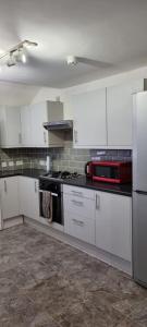 cocina con armarios blancos y fogones en 3 bed bedroom house with garden en Thamesmead
