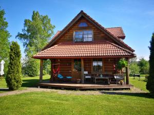 a log cabin with a porch in a yard at DvīņuMājas in Balvi