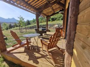 un porche de una cabaña con mesa y sillas en La Peyregoune, logement en pleine nature et table d'hôtes, en Blieux