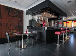 a restaurant with a bar with red chairs at Hotel Loob Madrid in Torrejón de Ardoz
