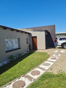 a house with a grass yard and a driveway at Tuvawa Luxury Suites in Walvis Bay