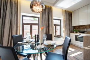 Angel Wing Apartamentai في فيلنيوس: غرفة طعام مع طاولة وكراسي زجاجية