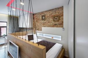 een slaapkamer met een schommelbed en een bakstenen muur bij Angel Wing Apartamentai in Vilnius