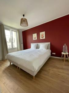 ein Schlafzimmer mit einem großen Bett mit einer roten Wand in der Unterkunft Le W - Appart vintage in Épernay
