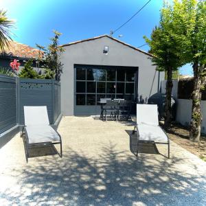 dos sillas y una mesa frente a una casa en Adorable Guest House avec balnéo et piscine en Olonne-sur-Mer