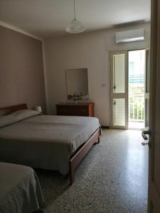 een slaapkamer met 2 bedden en een glazen schuifdeur bij Santa Maria al Bagno - 5 min. dal mare in Santa Maria al Bagno