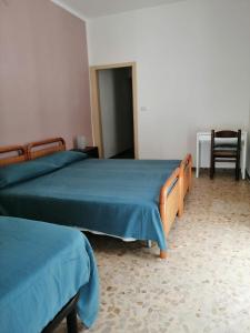 een slaapkamer met 2 bedden met blauwe lakens en een stoel bij Santa Maria al Bagno - 5 min. dal mare in Santa Maria al Bagno