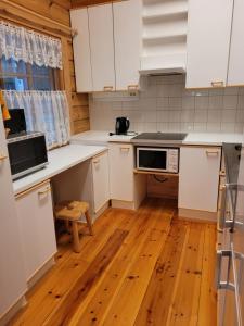 cocina con armarios blancos y suelo de madera en Lakeland Karelia Puutikka, en Kesälahti