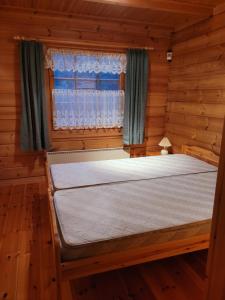 a bed in a wooden room with a window at Lakeland Karelia Puutikka in Kesälahti