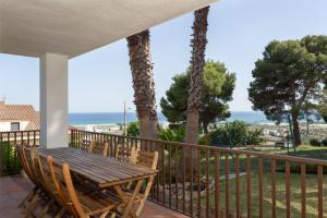 un portico con tavolo e sedie in legno sul balcone di Hauzify I Villa Formentor a Santa Susanna