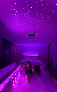 a woman sitting in a tub in a room with purple lights at Adorable Guest House avec balnéo et piscine in Olonne-sur-Mer +2 photos