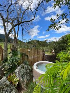 a hot tub in a garden with a fence at Cactus Chalé em lumiar in Lumiar