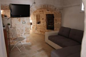ein Wohnzimmer mit einem Sofa und einem TV an einer Steinmauer in der Unterkunft Trullo Titti in Ostuni