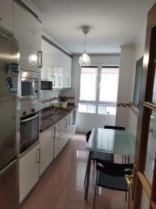 a kitchen with white cabinets and a glass table at Céntrico apartamento Oviedo Parking y wifi gratuitos Admite mascotas in Oviedo +4 photos