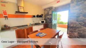a kitchen with a wooden table and a counter top at Quinta São Lourenço in Fajã da Ovelha