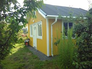 una pequeña casa amarilla con un banco en un patio en Attefallshus byggt 2019, en Helsingborg
