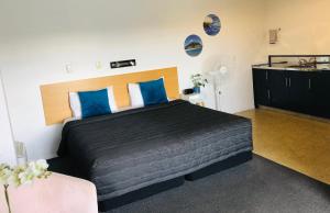 a bedroom with a large bed with blue pillows at Blue Haven Motel in Mount Maunganui