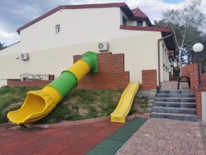 a yellow and green slide in front of a house at Bar Oaza in Szczerców