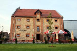 a large brick building with tables and umbrellas in front of it at Noclegi Złota Podkowa in Olszowa