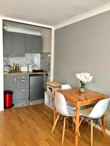 a kitchen with a wooden table and white chairs at Lovely Studio Room in the heart of Kingston upon Thames in Kingston upon Thames