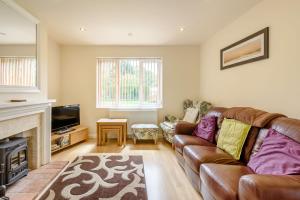 a living room with a leather couch and a fireplace at Woodland View in West Barkwith