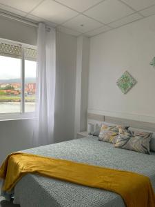 Un dormitorio con una cama con una manta amarilla encima. en La bahia, en Moaña