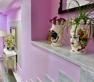 two vases on a shelf in a room with purple walls at Hotel Scilla in Scilla