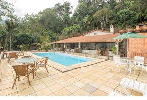 a patio with a table and chairs and a pool at Hotel Boutique Pé Da Tartaruga in Teresópolis