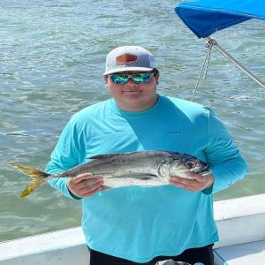 a man standing on a boat holding a fish at Ocean Tide Beach Resort in San Pedro