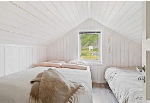 two beds in a white room with a window at Lofoten Links Lodges in Gimsøy