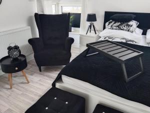 a bedroom with a black bed and a chair at Willa La mer in Ustka