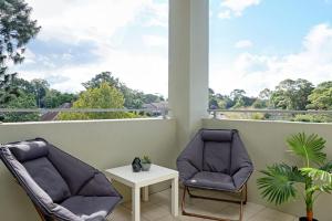 2 sillas y una mesa en el balcón en Large Premium Warrawee Apartment with Parking A401 en Warrawee