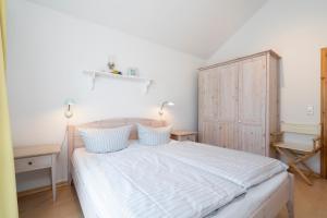 1 dormitorio con 1 cama y armario de madera en Strandpark Sierksdorf H085, en Sierksdorf