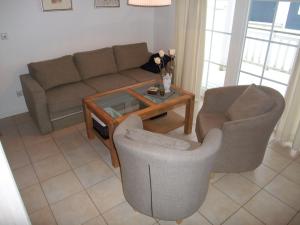 ein Wohnzimmer mit einem Sofa, 2 Stühlen und einem Tisch in der Unterkunft Strandpark Sierksdorf H090 in Sierksdorf