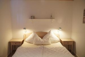 Schlafzimmer mit einem Bett mit weißer Bettwäsche und Kissen in der Unterkunft Strandpark Sierksdorf H090 in Sierksdorf