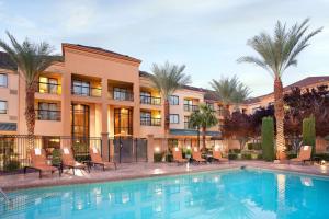 einem Pool vor einem Gebäude mit Palmen in der Unterkunft Sonesta Select Las Vegas Summerlin in Las Vegas