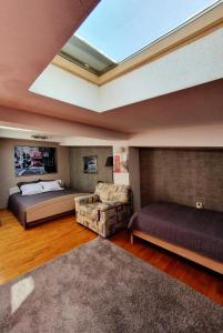 a bedroom with two beds and a couch and a skylight at Central Station Skopje in Skopje